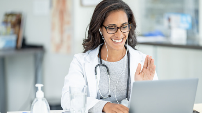 Doctor smiling and waving during a Telehealth appointment.