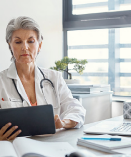 Medical professional sitting and reviewing information on a tablet.