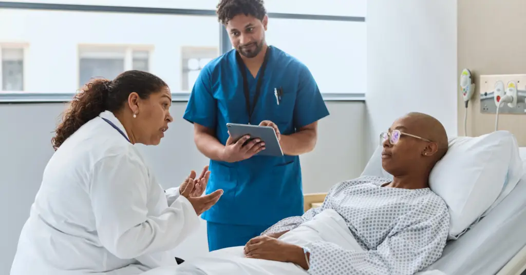 physician and nurse speak to patient at bedside