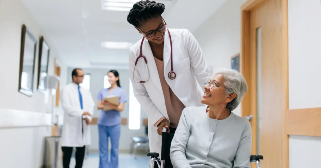 physician smiles at patient in a wheelchair in hospital