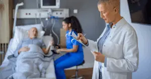 doctor making notes for patient in hospital bed