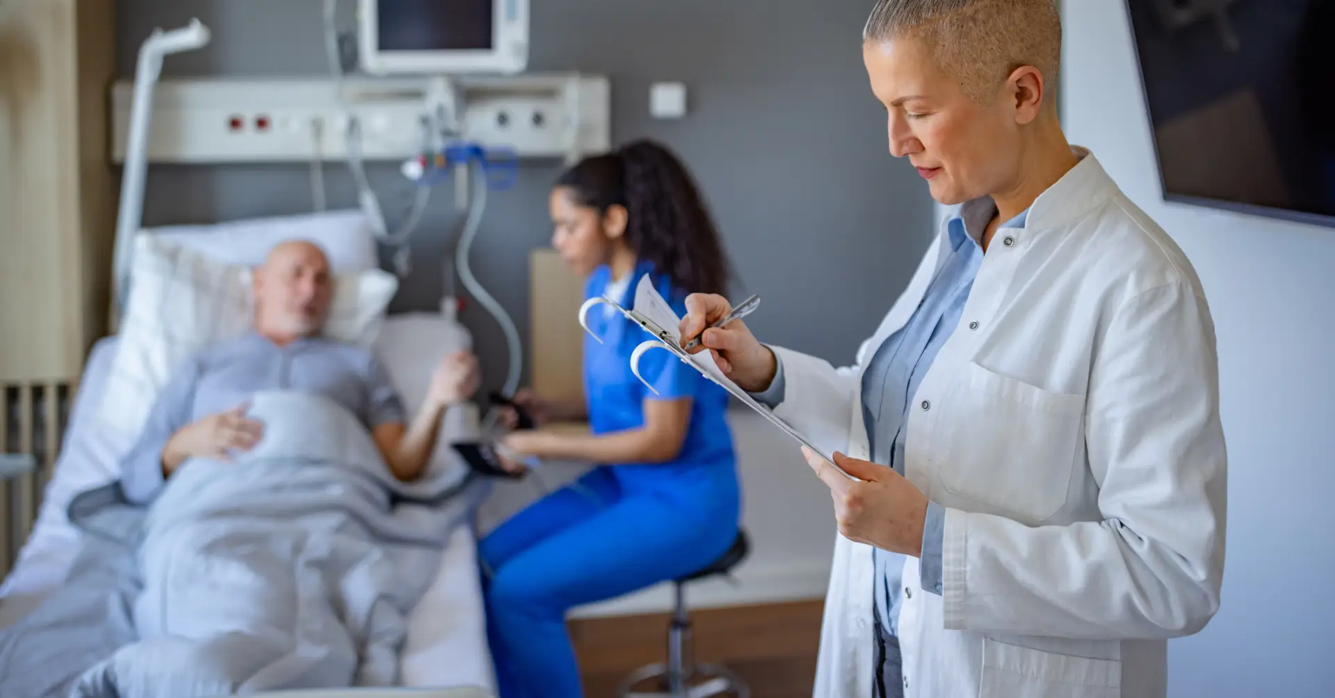 doctor making notes for patient in hospital bed