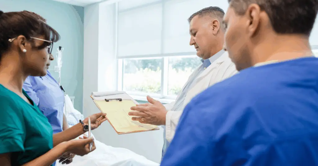 group of doctors discussing patient chart in hospital room
