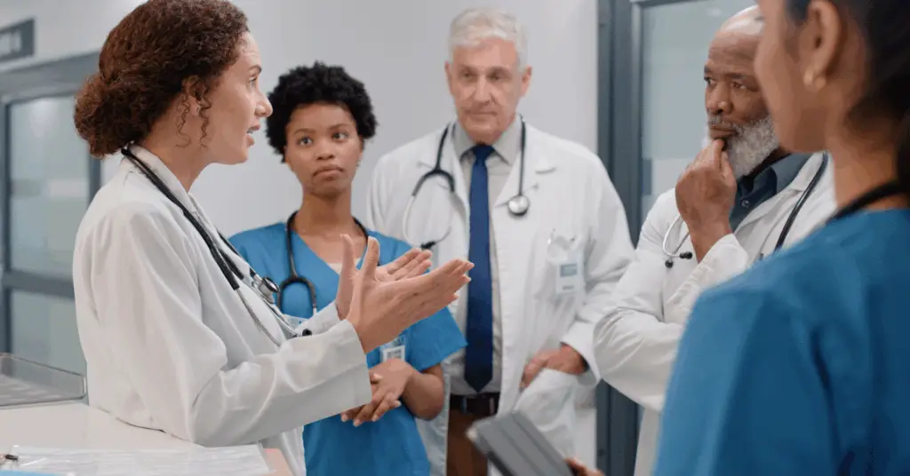 physician talking with a group of doctors in a hospital
