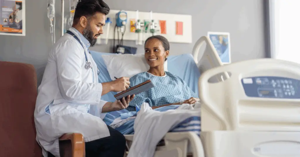 doctor talking with patient at bedside in hospital writing on tablet