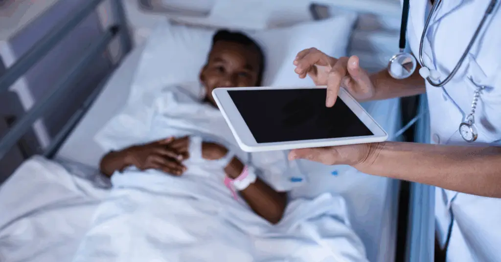 doctor makes notes on tablet near patient in hospital bed