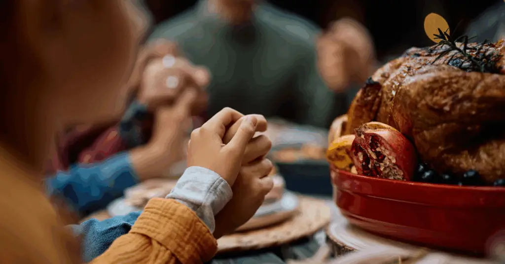 family holding hands at dinner table