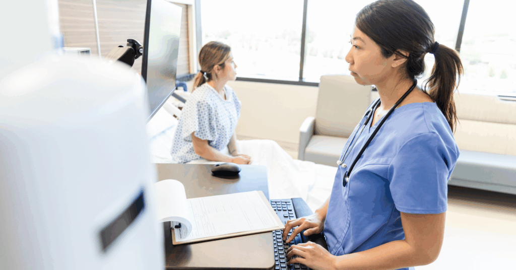 nurse charting patient information in hospital room