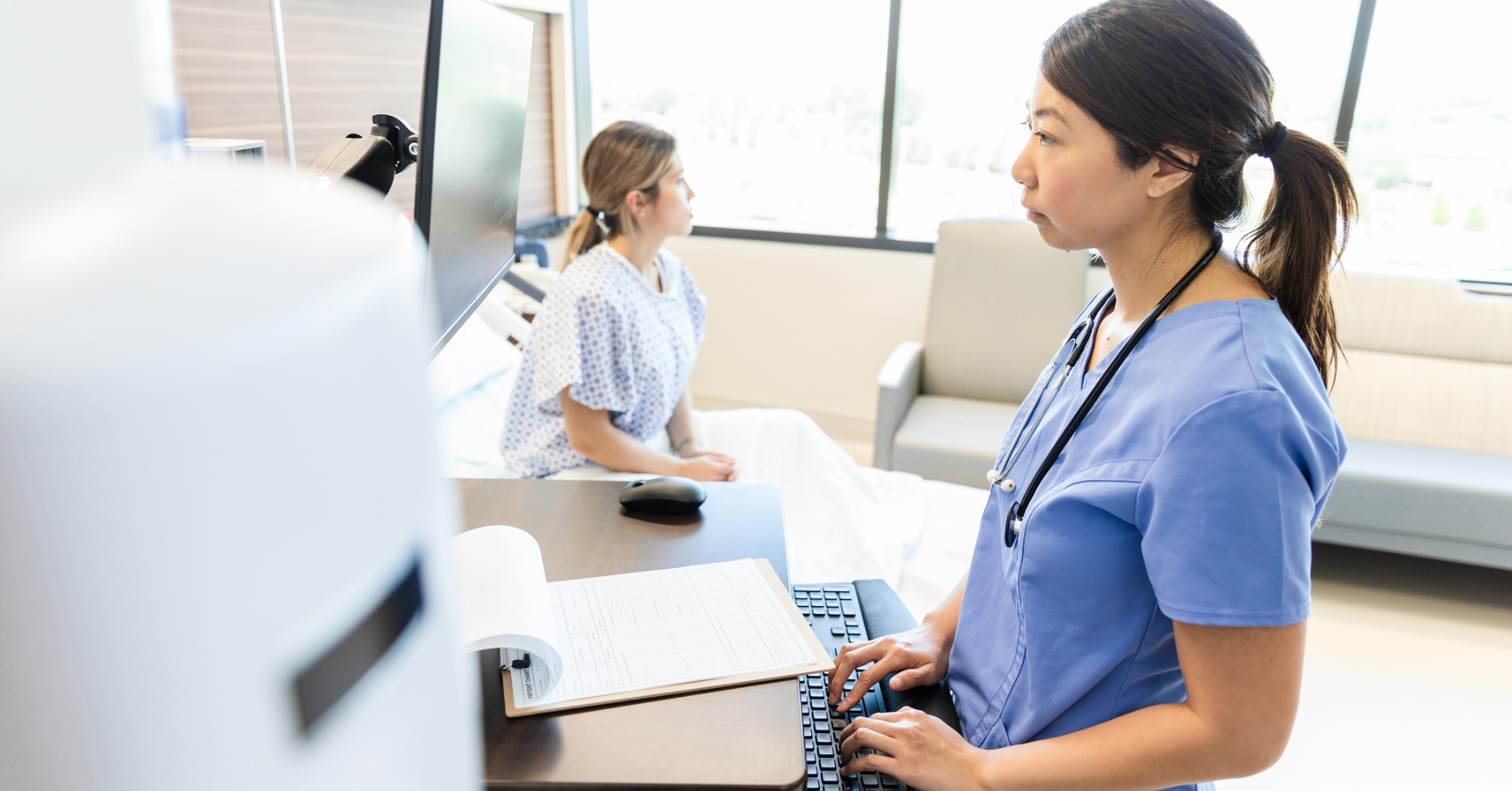 nurse charting patient information in hospital room