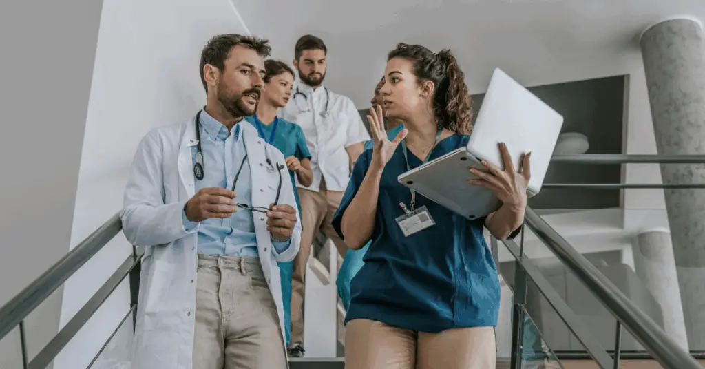 group of medical professionals talking over a computer while walking through hospital