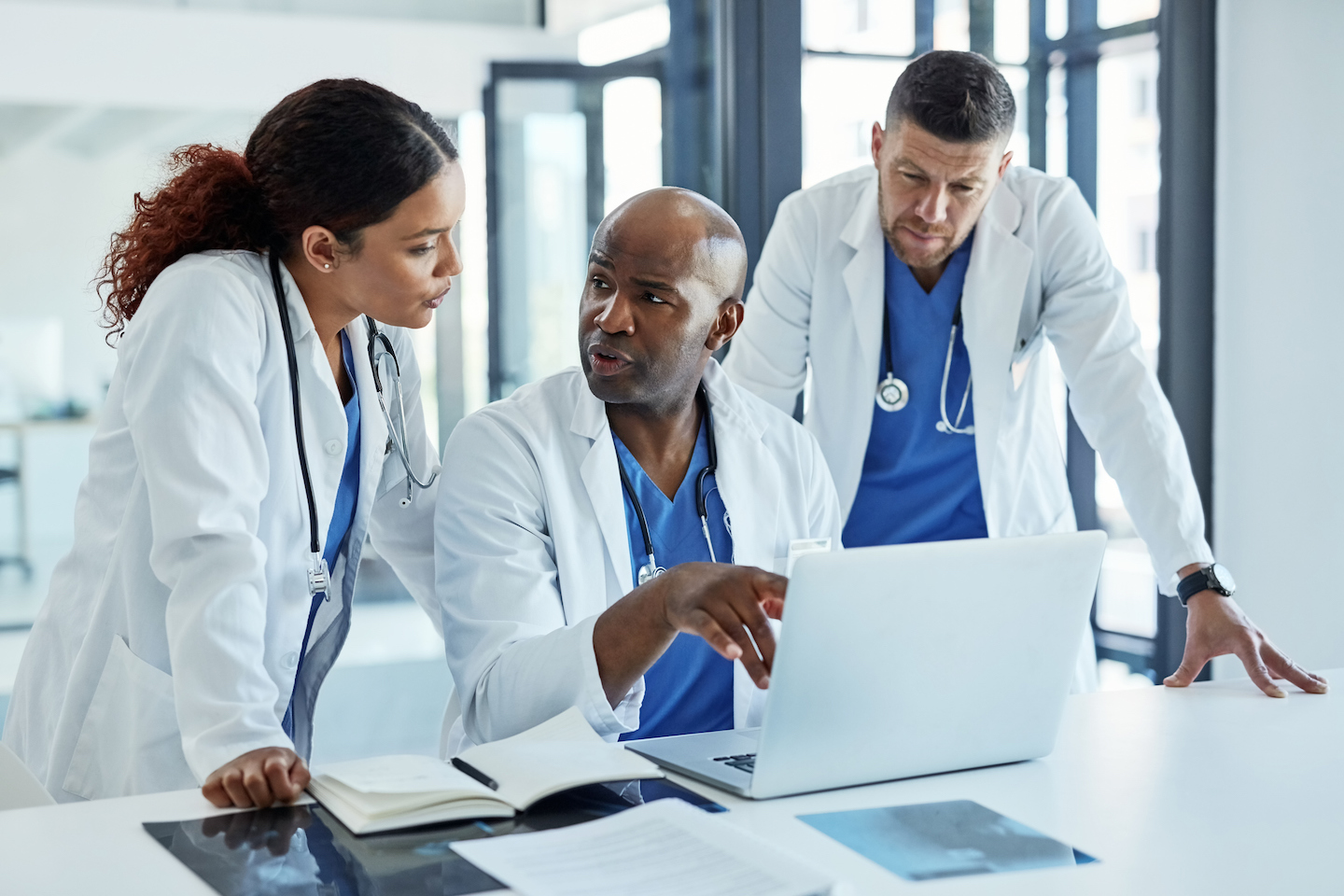 Diverse group of medical professionals discussing while looking at a laptop.