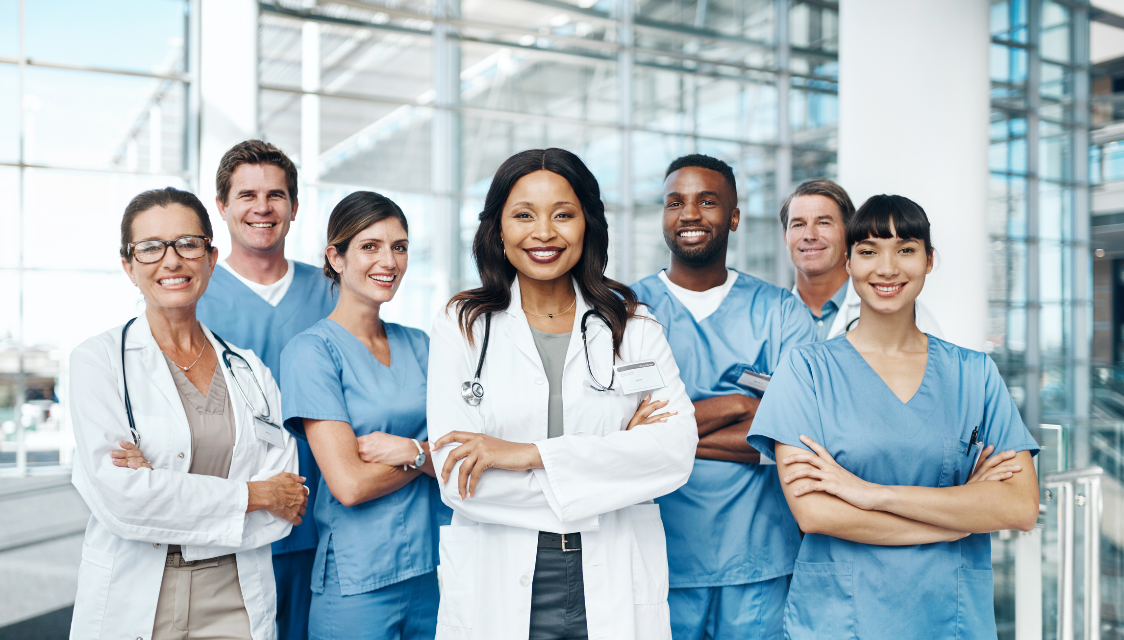 Diverse group of medical professionals crossing arms and smiling.