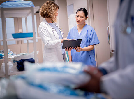 Doctor discussing with nurse over clipboard.