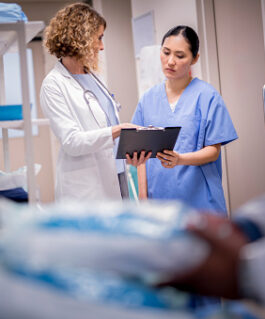 Doctor discussing with nurse over clipboard.