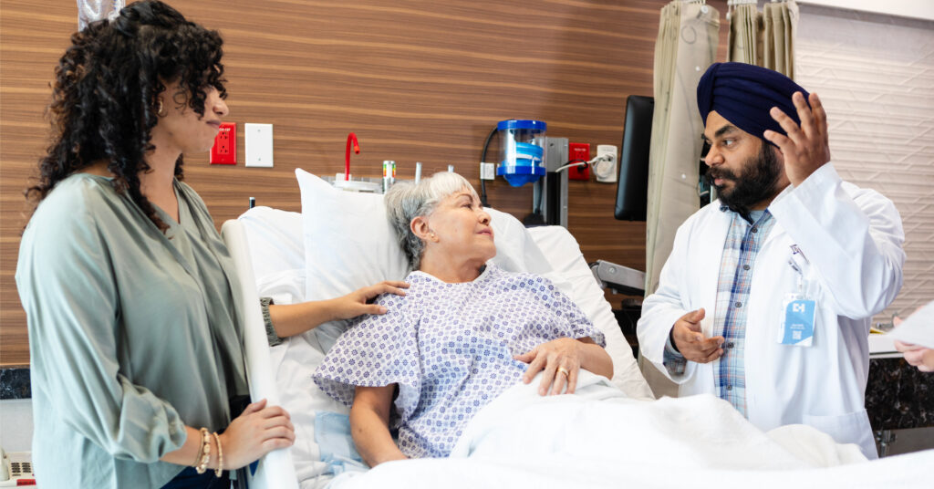 Muslim physician speaks with Hispanic mother and daughter at the mother's hospital bed side