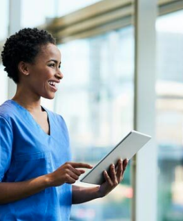 Medical professional smiles while holding a tablet.