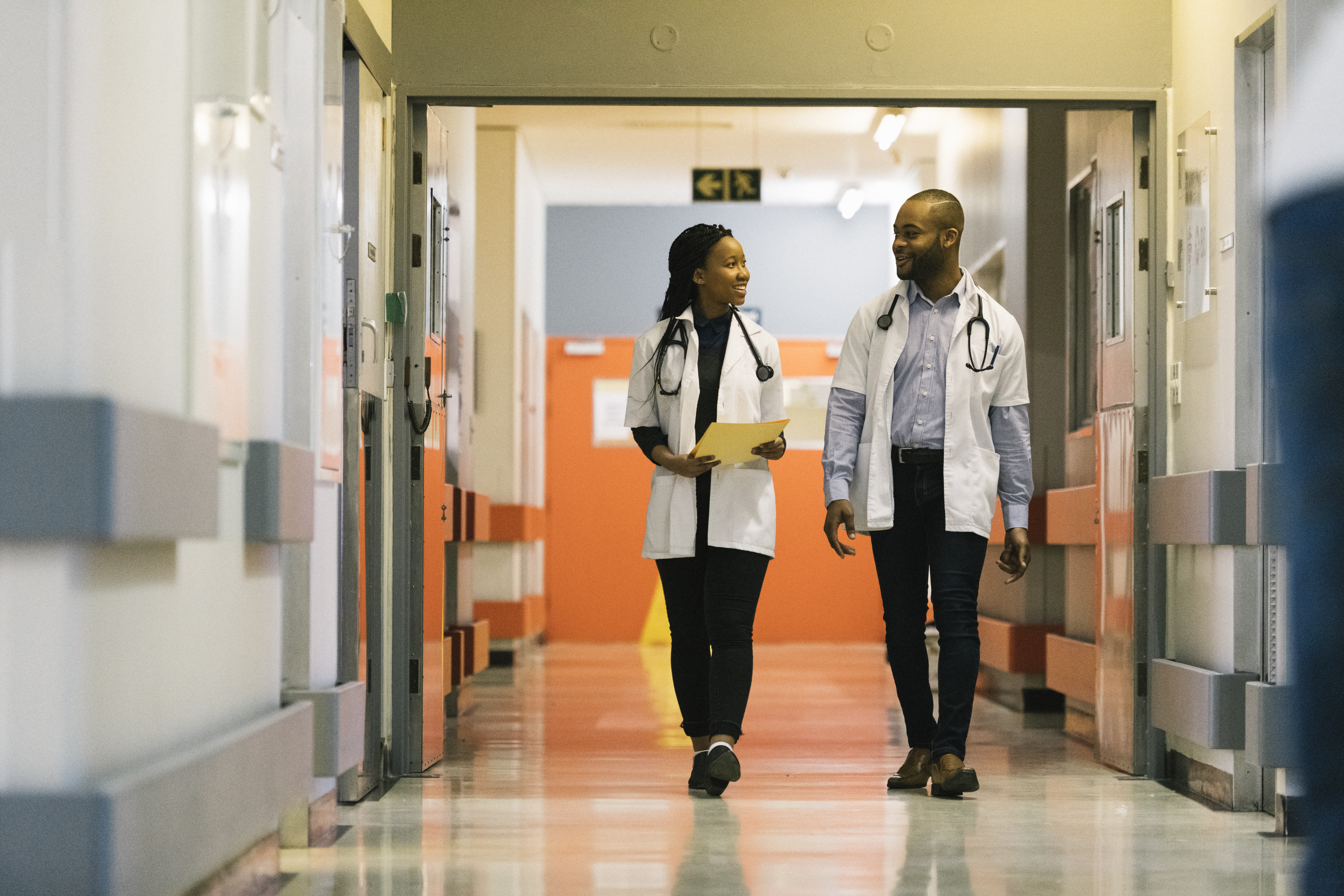Two medical professionals talking while walking down a corridor.