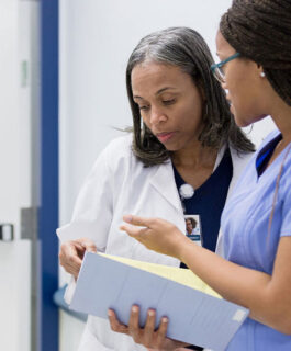 Nurse holding a document while talking to a doctor.