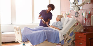 Nurse engaging with an elderly patient in a hospital bed.