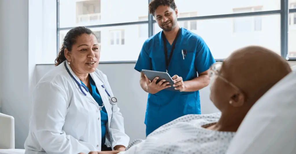doctor and nurse talking to patient in hospital bed
