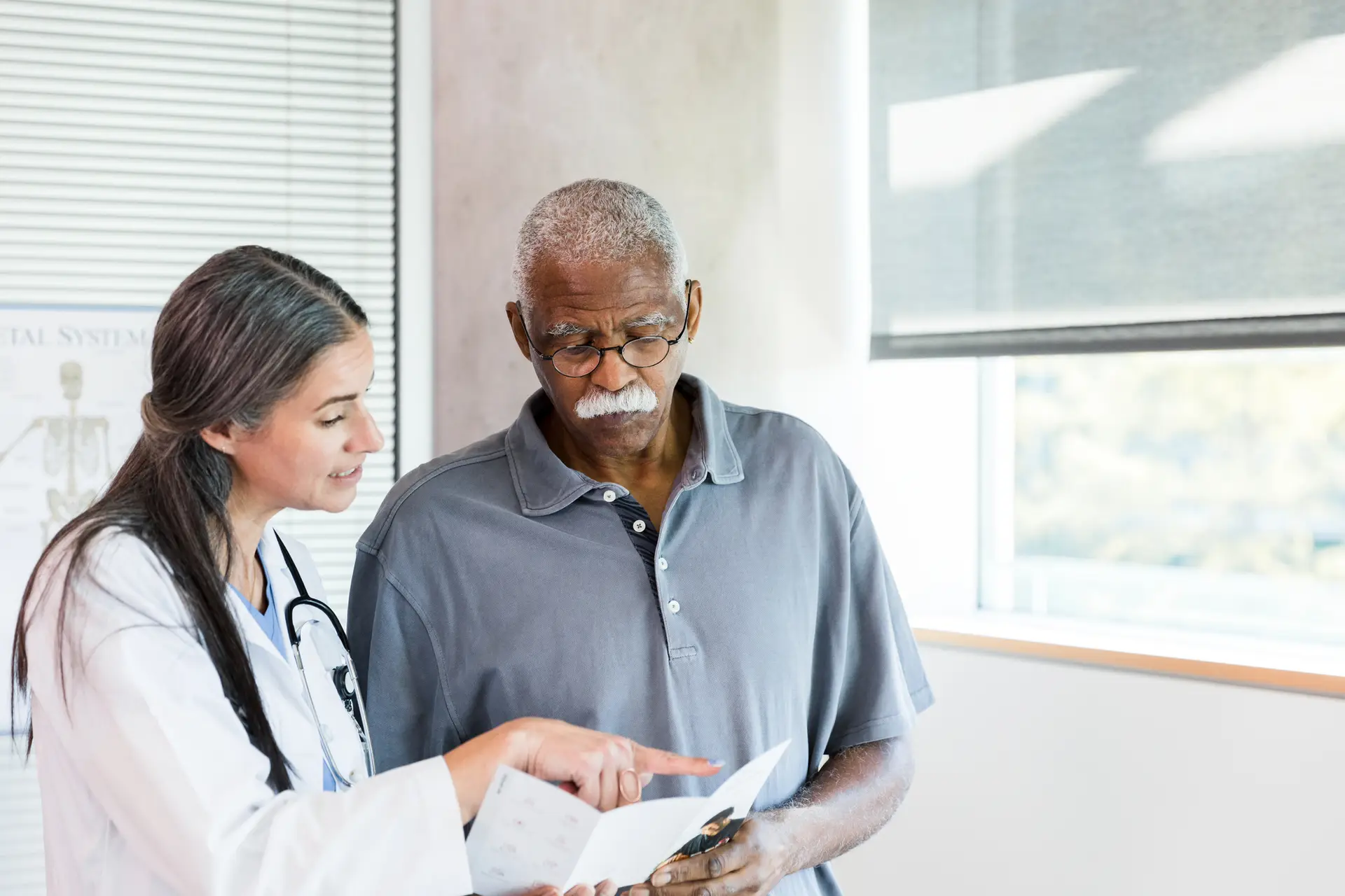 Female doctor explains brochure information to senior man