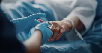nurse holding patient hand in hospital bed