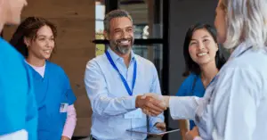 hospital exec shakes hands with physicians while speaking in a group in a hospital