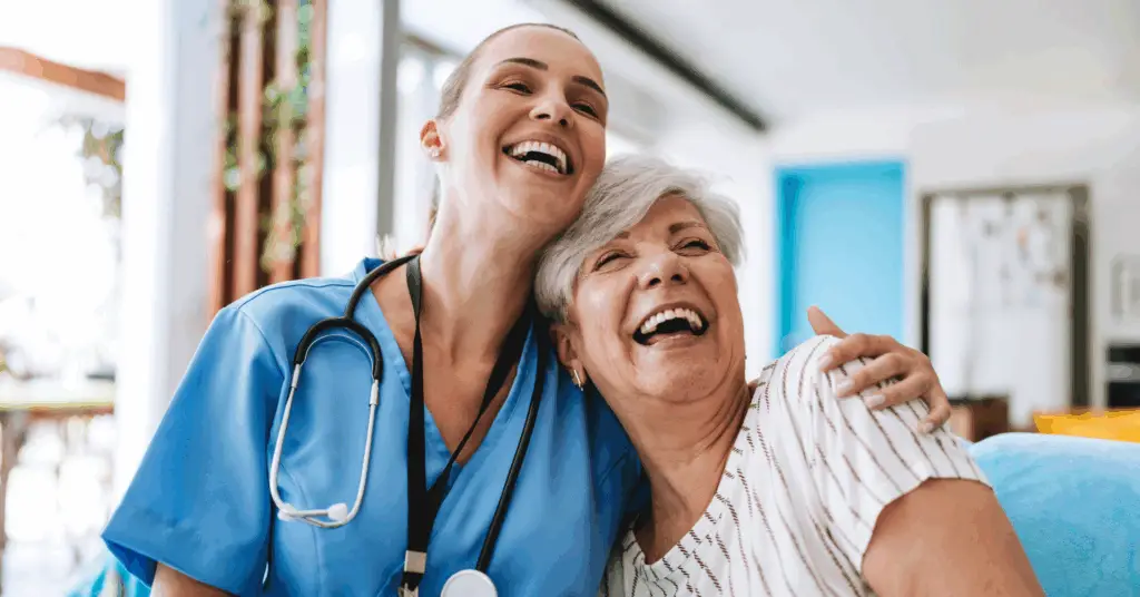 nurse hugging and smiling with an older female patient