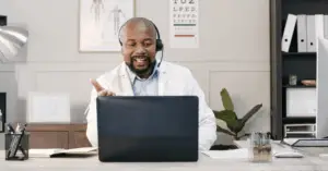 male doctor talking to patient over headset in front of computer