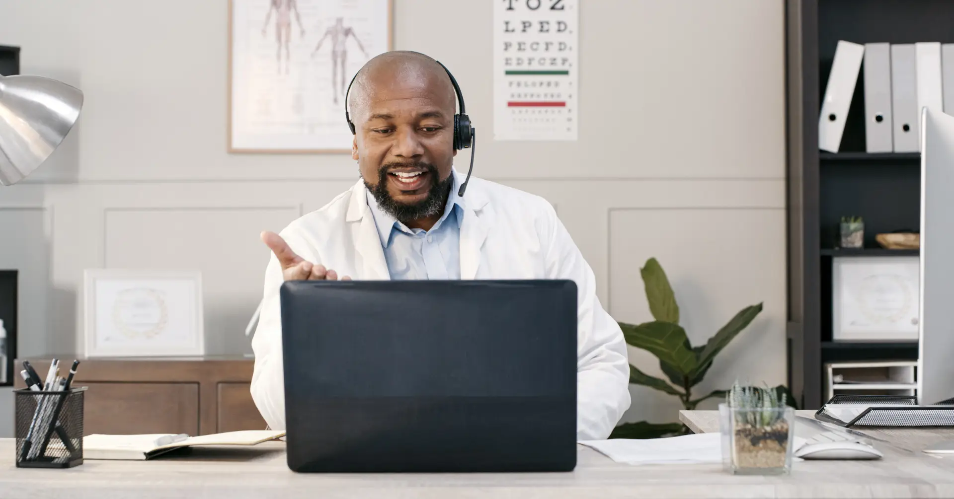 male doctor talking to patient over headset in front of computer