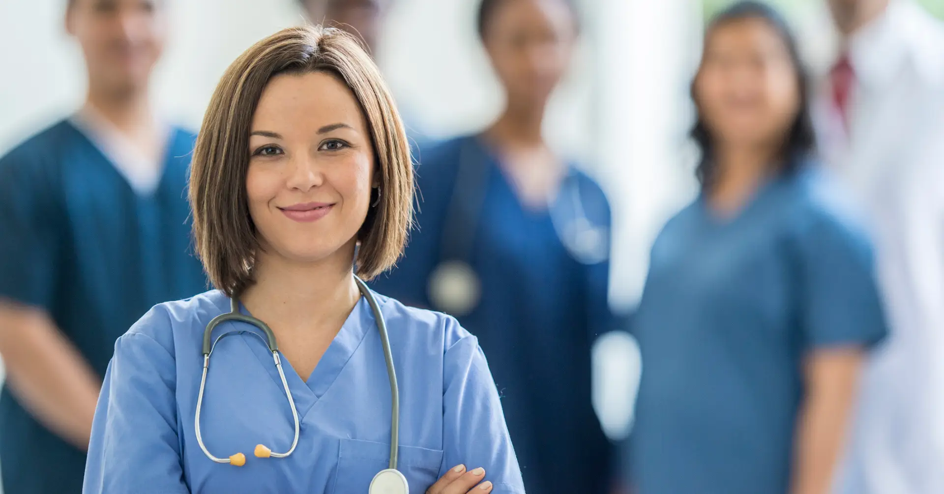 resident physician smiles at camera with other residents in background