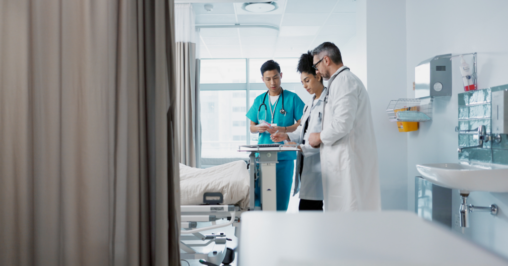 Doctors and nurse speaking at a patients bedside