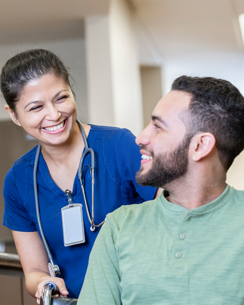 Female nurse and patient sharing a heartfelt conversation as she pushes the patient in a wheelchair
