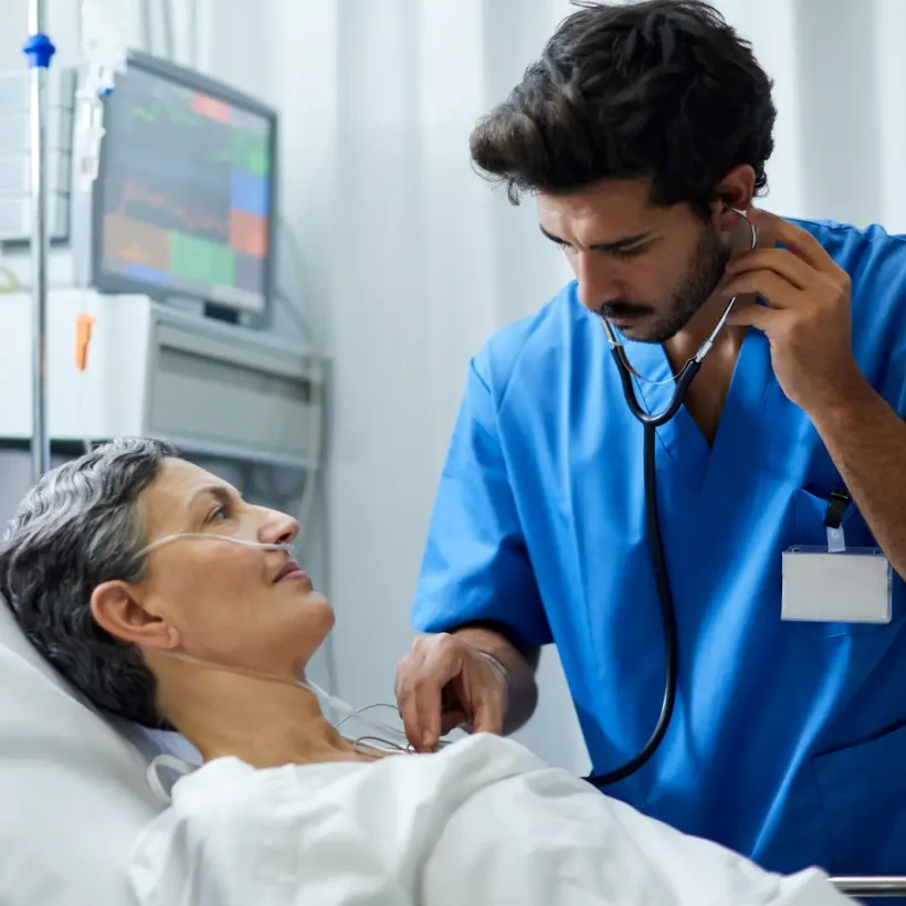 Nurse listens to patient's heart as they lie in a hospital bed; np and pa clinical careers