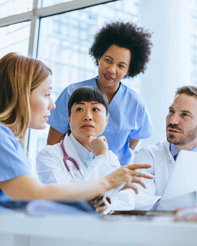 Doctors and nurses discussing care plans at a conference table, highlighting collaborative hospital medicine services.